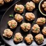 A platter of sausage balls with a dish of hot honey for dipping