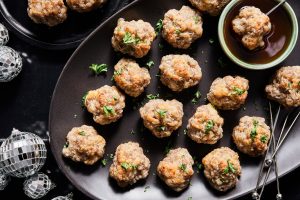 A platter of sausage balls with a dish of hot honey for dipping