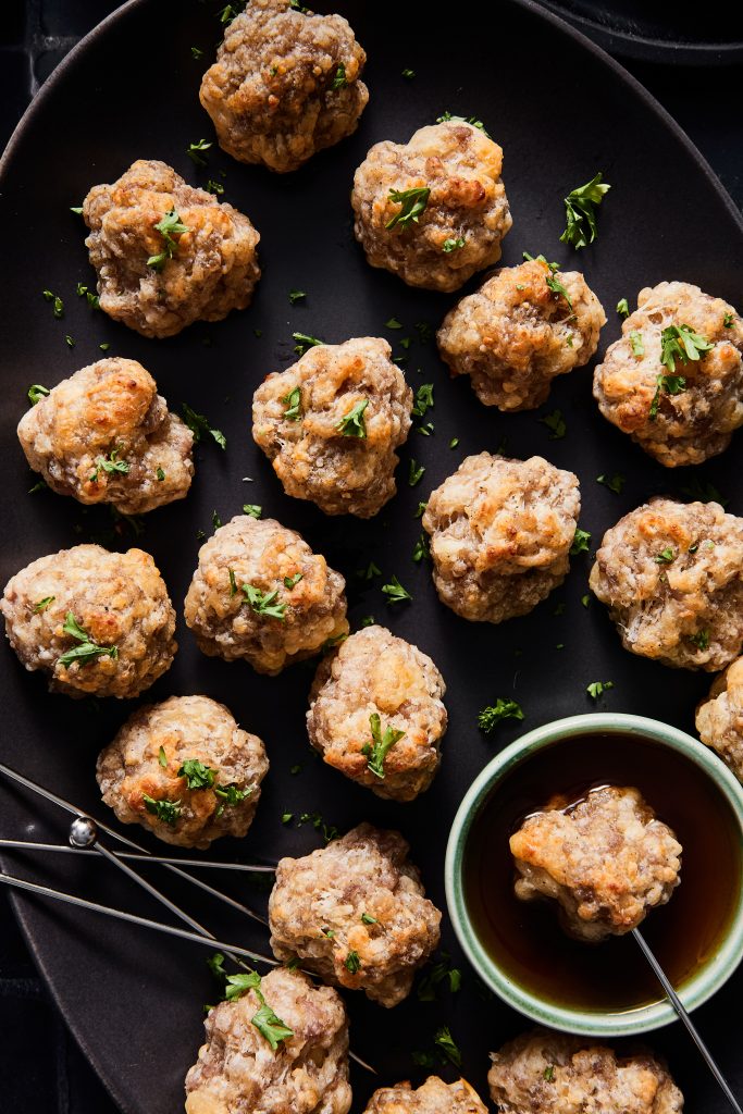 Black platter of sausage balls with hot honey for dipping