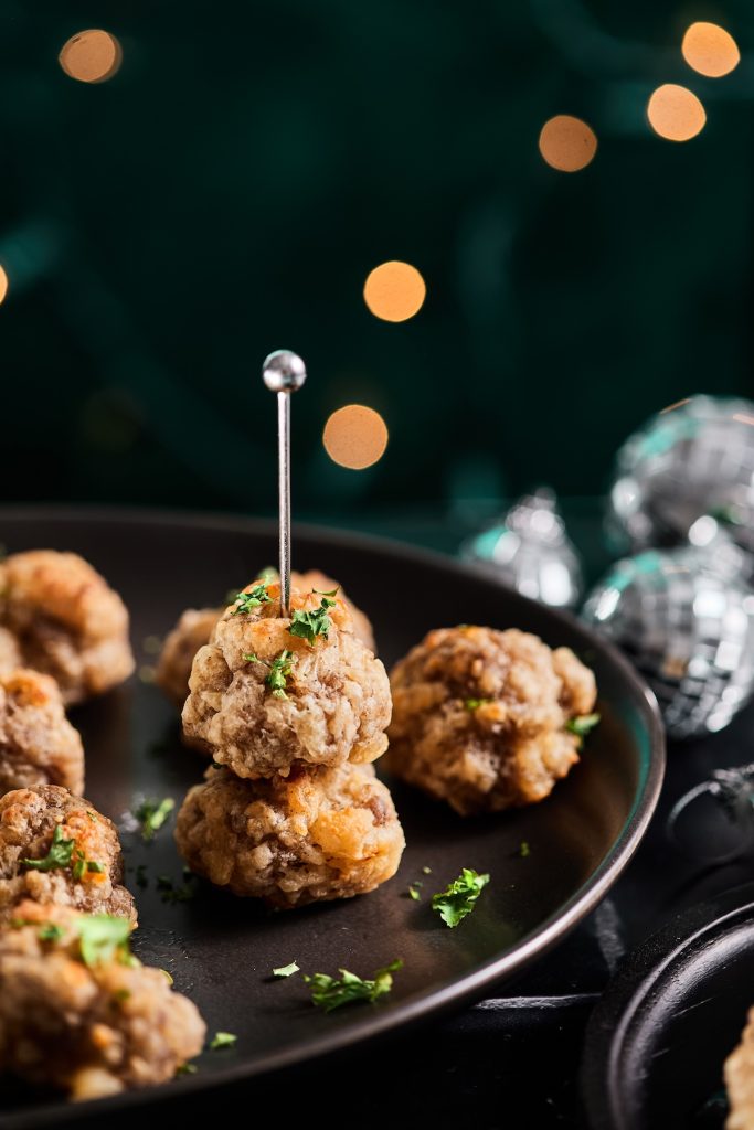 Stack of sausage balls with a toothpick on a black platter 