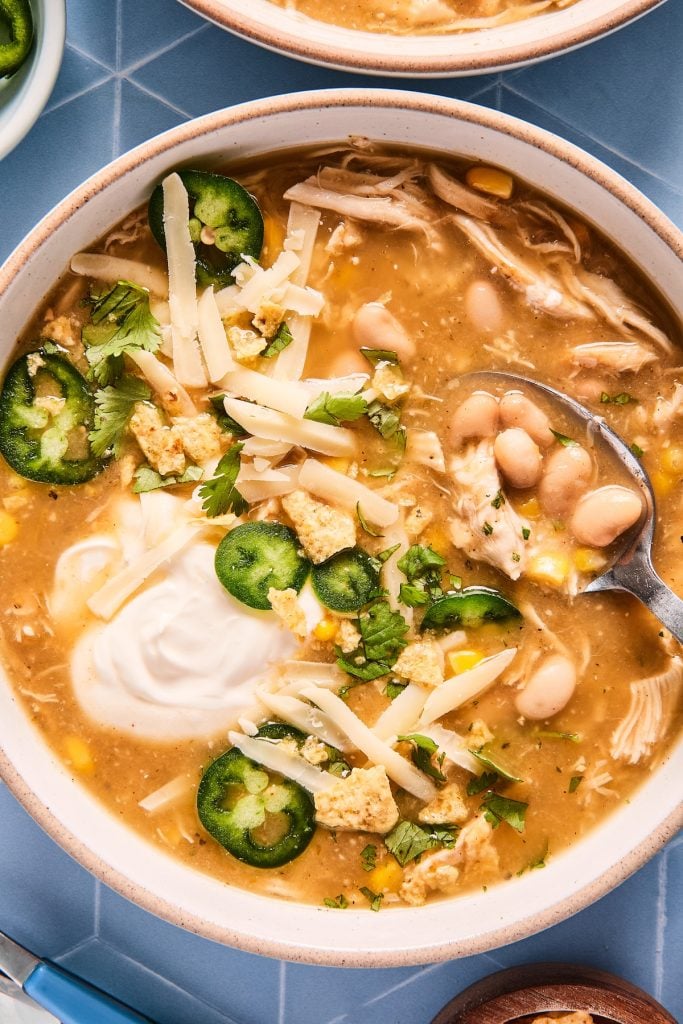 Bowl of easy white chicken chili in slow cooker with spoon and garnishes