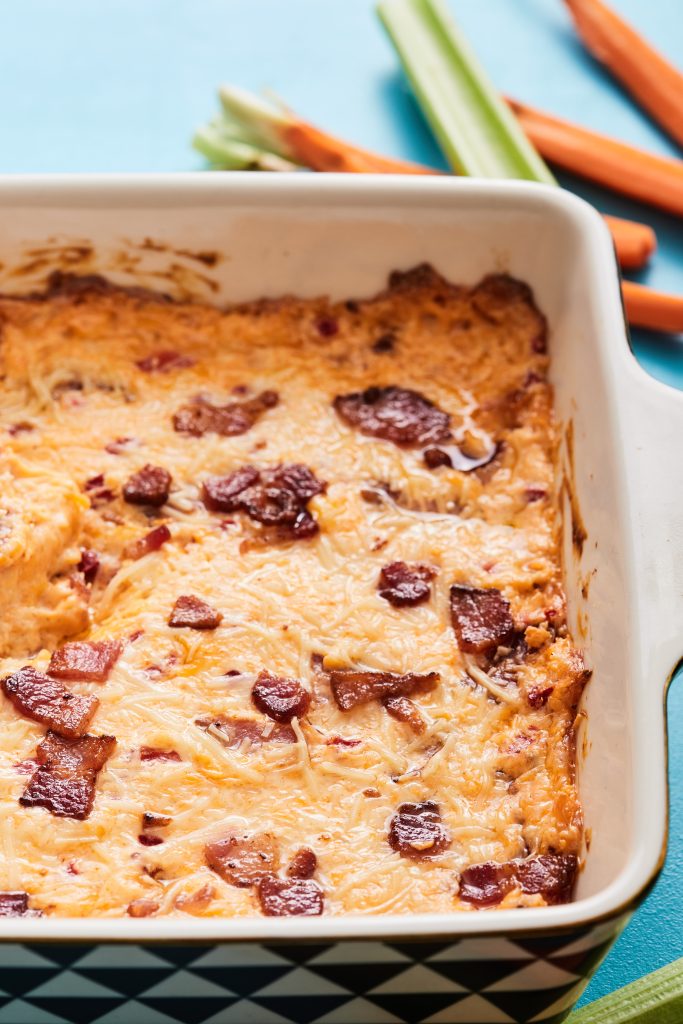 Baking dish full of pimento cheese dip with crumbled bacon on the top