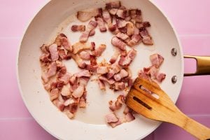 Sliced bacon in a skillet cooking