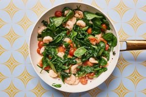 Skillet with cooked shrimp, tomatoes and spinach