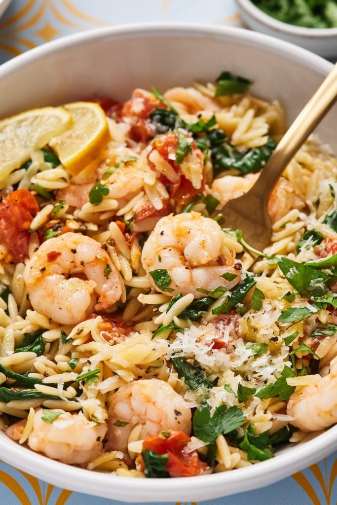 Shrimp and orzo in a bowl with a gold fork